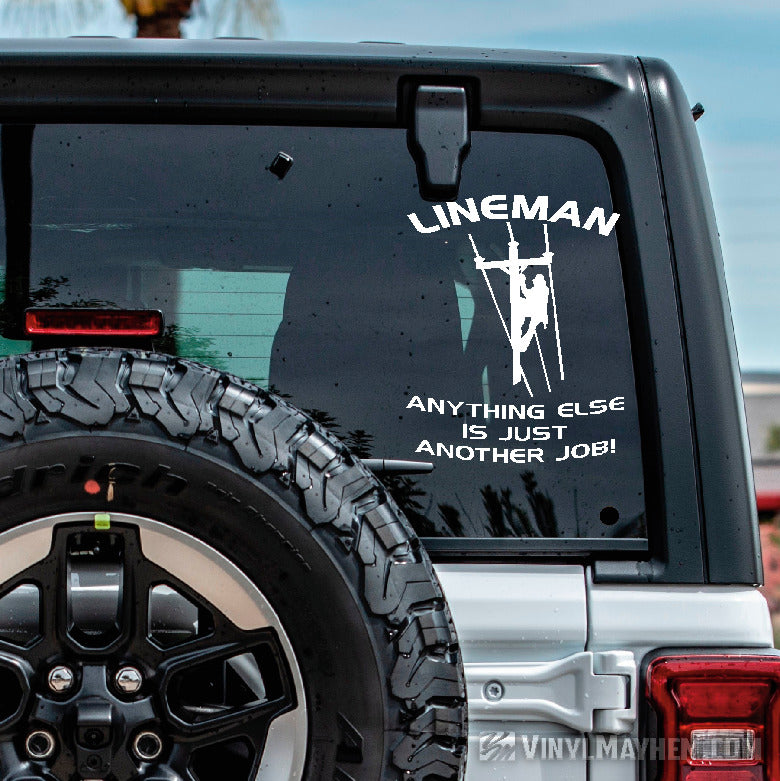 Car window with a decal that reads 'Lineman Anything Else is Just Another Job' on a clear day.