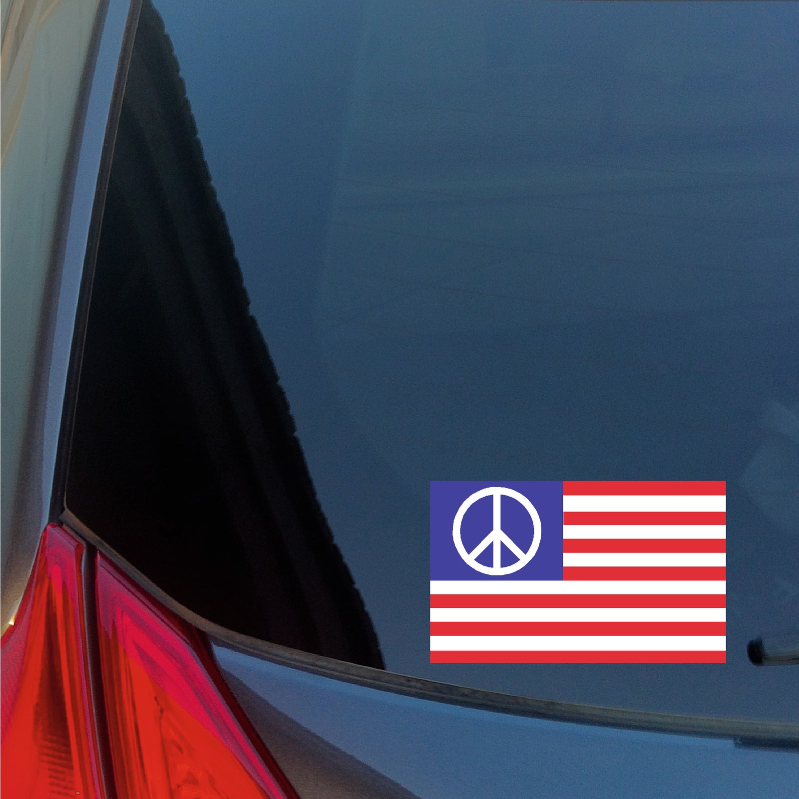 Peace symbol on an American flag decal on a car window